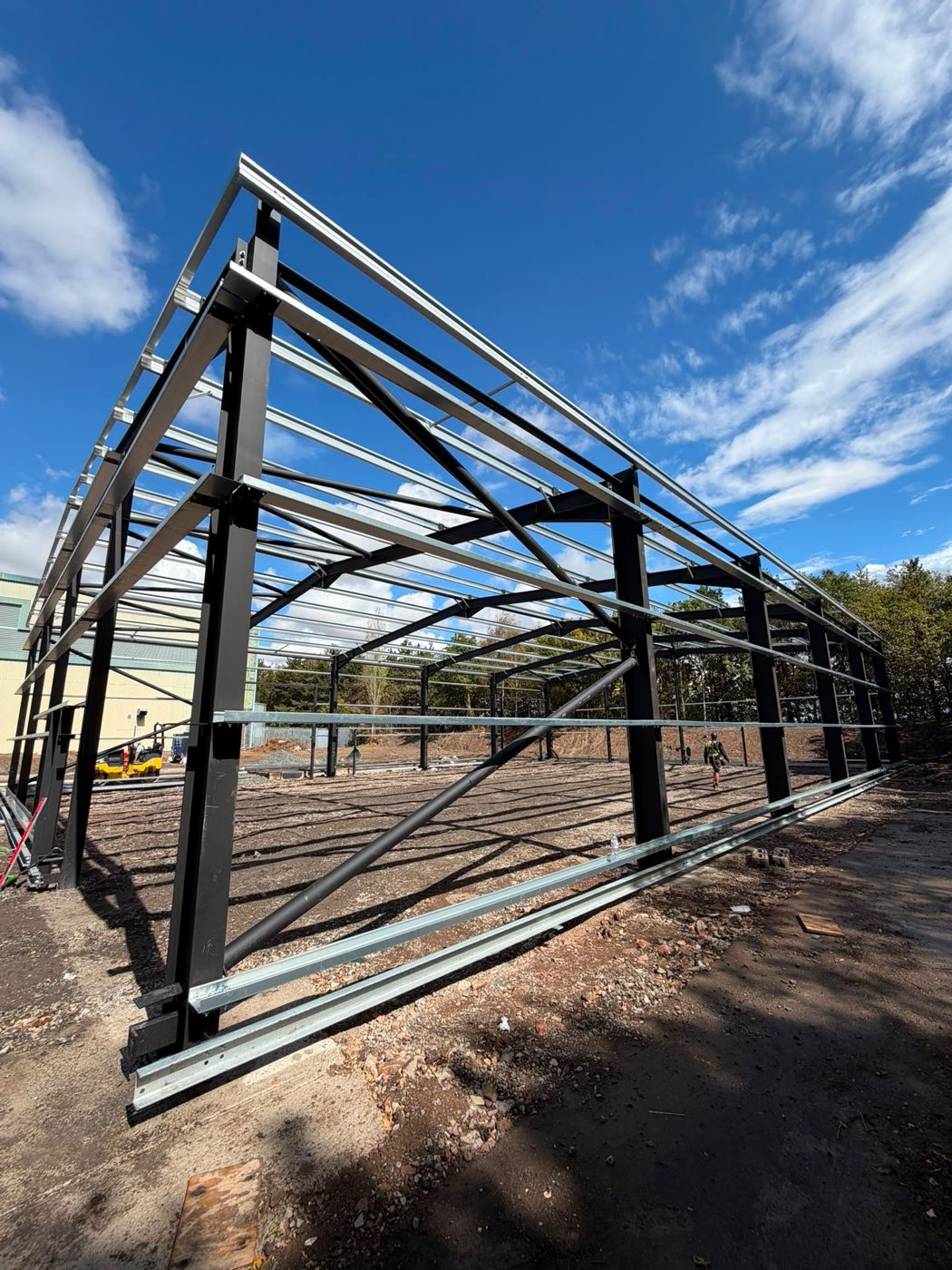 Corner view of the steel frame showing the black columns and galvanised roof rails